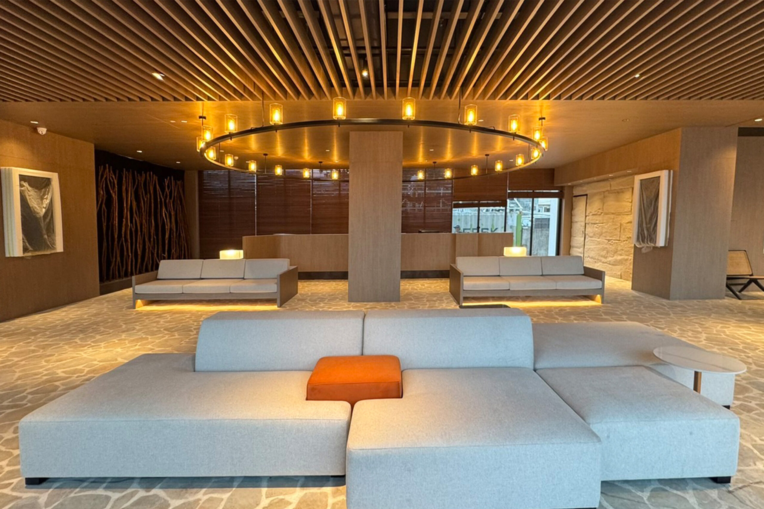 Office lounge with dark wooden and white walls, tiled floor, white sofa and armchairs and two round coffee tables with laptop standing on the carpet. Conference room next to it. 3d rendering